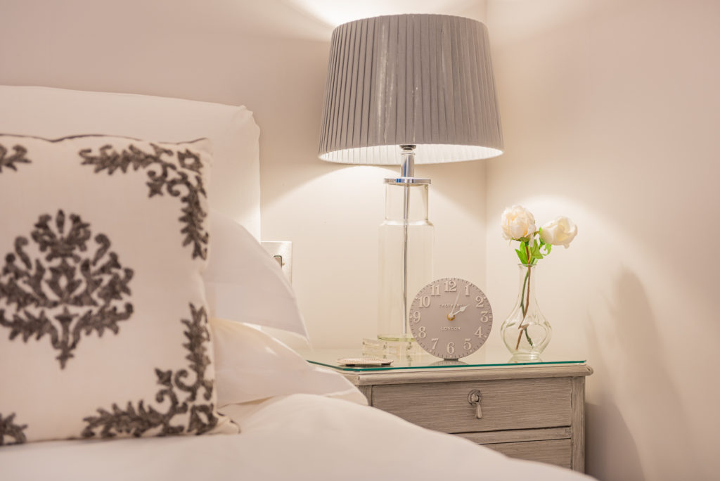 Bedside table with clock and lamp in grey and white colour scheme